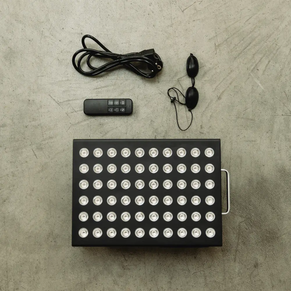 Draufsicht auf den Lieferumfang des Reboots Relight Mini: Das LED-Panel von oben, Kabel, Fernbedienung und Schutzbrille auf Betonboden.