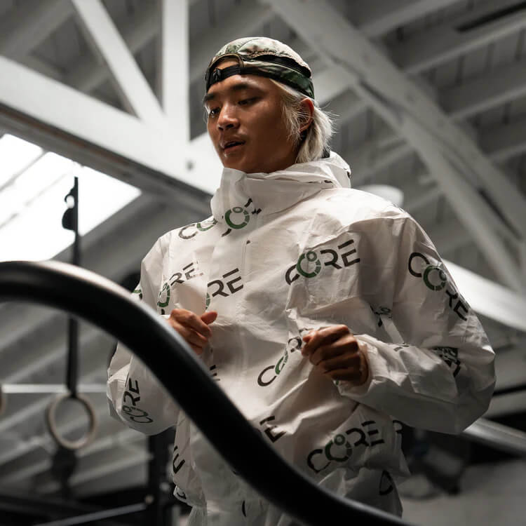 Nahaufnahme eines Athleten im weißen CORE 2 Heat Training Suit beim schweißtreibenden Ausdauertraining auf dem Laufband Nahaufnahme eines Athleten im weißen CORE 2 Heat Training Suit beim schweißtreibenden Ausdauertraining auf dem Laufband