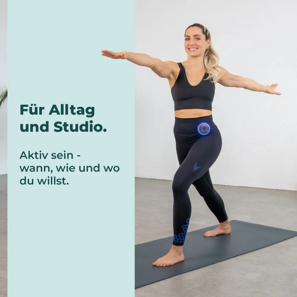 Eine lächelnde Frau barfuß auf einer Yogamatte in einer Krieger-Pose beim Training im Studio mit der schwarzen Antelope EMS-Leggings. Links steht der Text „Für Alltag und Studio. Aktiv sein - wann, wie und wo du willst.“.